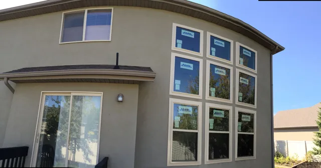Exterior of a house with several new windows, blue sky, and a sliding glass door.